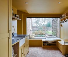 a kitchen with an open window and brick flooring, along with wooden cabinetry