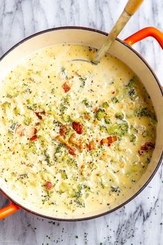 a pot filled with broccoli and cheese on top of a marble countertop