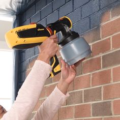 a woman is using a power tool on a brick wall