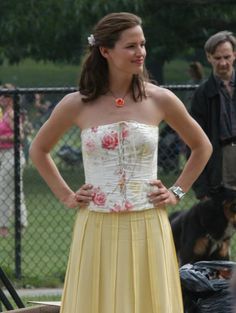 a woman in a yellow dress standing next to a dog