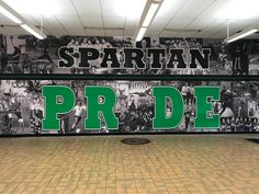 a large sign that says spartan pride in front of a wall with pictures on it