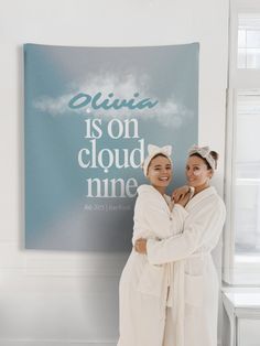 two women standing next to each other in front of a wall with a sign on it