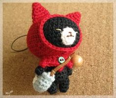 a crocheted black and white cat with a red jacket