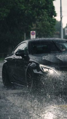 a black car driving through a flooded street