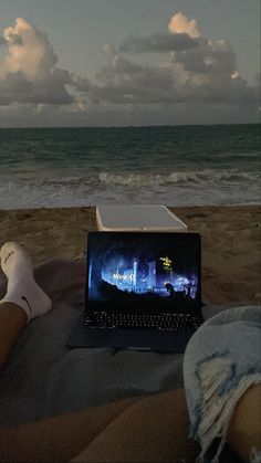 a laptop computer sitting on top of a beach next to the ocean