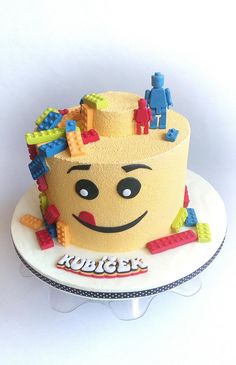 a birthday cake with legos on it is sitting on a white plate and has a happy face in the middle