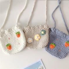 three crocheted purses are hanging on a white wall next to a magazine