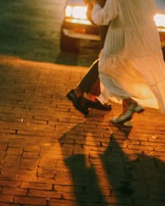 a woman walking down the street with an umbrella over her head and shoes in front of her