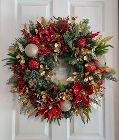 a christmas wreath on the front door with ornaments and greenery hanging from it's sides