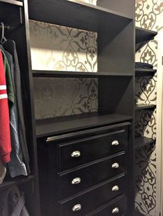 a closet with black drawers and white wallpaper