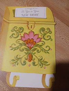 a yellow mailbox with a pink flower on the front and green leaves on the back