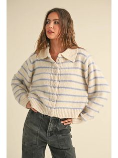 a woman wearing a striped sweater and jeans with her hands on her hips, looking off to the side