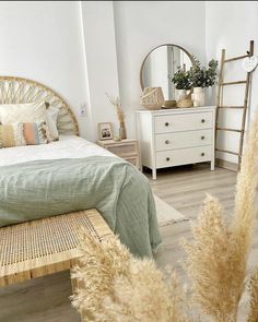 a bedroom with a bed, dresser and mirror on the wall next to plants in vases