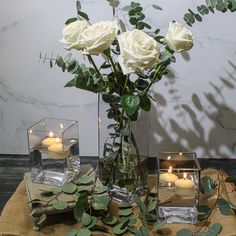 white roses and candles in glass vases on a table