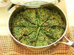 a large pot filled with green vegetables on top of a table