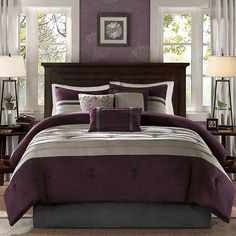 a bed in a bedroom with purple and white comforter