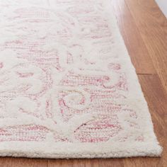 a white and pink rug on top of a wooden floor