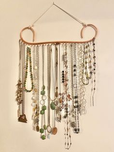 a wall hanging with lots of necklaces and rings on it's side,