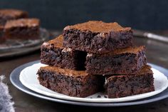 chocolate brownies stacked on top of each other on a plate with one piece cut out