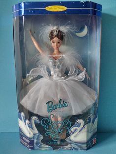 the barbie doll is in its box and it's wearing a white dress with feathers