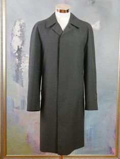 This charcoal gray overcoat is crafted from a high-quality wool-blend fabric, has a notch collar, and closes in the front with three concealed black buttons. The raglan style long sleeves feature a buttoned cuff strap, and the coat has two slanted storm pockets. The coat is lined in a black satin polyamid fabric (with one inner pocket), and a center vent in the back ensures complete ease of movement. Brand label: Oratop (Finland) Size: 44 US/UK Material: 45% Wool, 55% Polyester Condition: Near M Gray Wool Coat With Lapel Collar And Button Closure, Gray Wool Coat With Lapel Collar, Gray Wool Coat With Button Closure, Classic Gray Wool Coat For Winter, Gray Single-breasted Wool Coat With Lapel Collar, Gray Wool Single-breasted Outerwear, Gray Single Breasted Outerwear With Lapel Collar, Gray Fitted Wool Coat With Pockets, Classic Gray Wool Coat For Fall