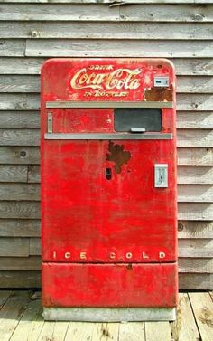 an old coca cola machine sitting on top of a wooden deck