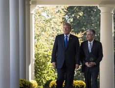 two men in suits and ties are walking through an archway with columns on either side