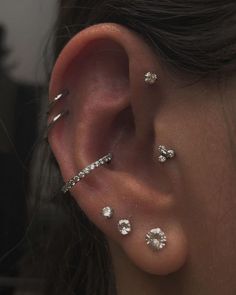 a woman's ear with three different piercings