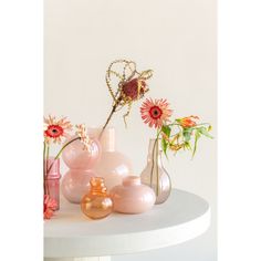 several vases with flowers in them sitting on a white table top next to each other