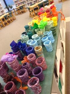 several stacks of colorful plastic wrapped objects on a long table in the middle of a library