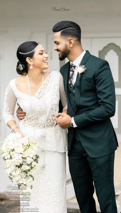 a man and woman standing next to each other in front of a white building with flowers