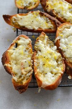 several pieces of bread with cheese and herbs on them sitting on a cooling rack,