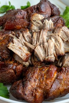 some meat is on a white plate and garnished with cilantro leaves