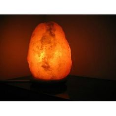 a himalayan rock lamp on a table in front of a dark background with the light reflecting off it's surface