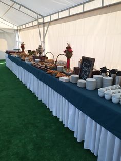 a long table covered in plates and bowls with food on it's sides under a tent