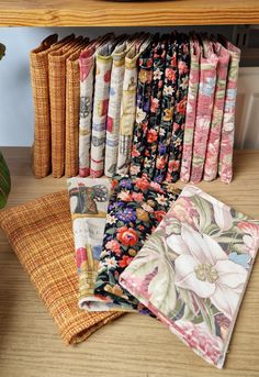 a bunch of fabric sitting on top of a wooden table next to a potted plant