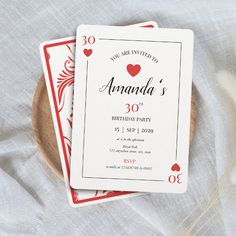 two playing cards sitting on top of a wooden plate next to some white and red flowers