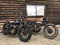 two motorcycles parked next to each other in front of a wooden building with shark teeth on it