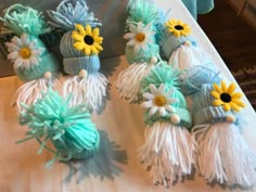 several knitted hats with flowers and tassels on top of a white table