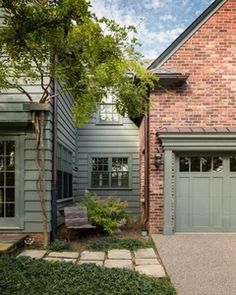 a brick house with green garage doors and stone walkway leading to the front door area