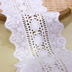 a piece of white lace sitting on top of a table next to a bamboo basket