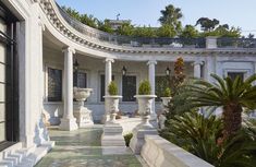 an outdoor courtyard with columns and potted plants