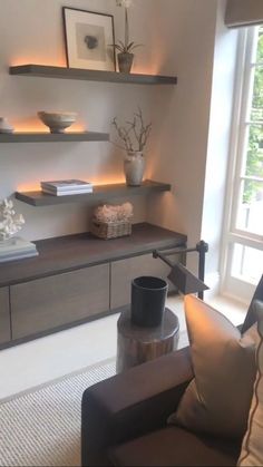 a living room filled with furniture and shelves next to a large window on top of a hard wood floor