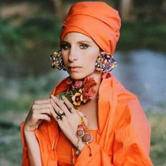 a woman wearing an orange outfit with flowers in her hair and jewelry around her neck