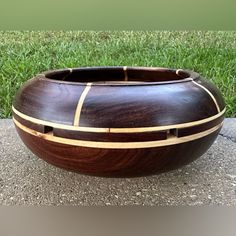 a large wooden bowl sitting on top of a cement ground next to green grass in the background