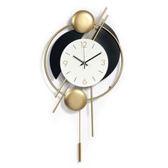 a black and white clock with two gold balls on the front, and an orange ball on the back