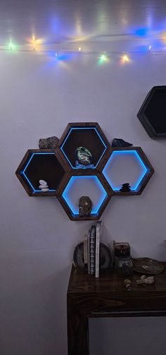 three hexagonal shaped shelves with lights above them on the wall behind a desk