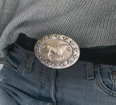 Western concho belt buckle with galloping horse in sculptural relief in polished silvery pewter. Buckle measures 3 1/2 X 2 3/4 inches and has a standard 1 1/2 inch belt loop and a decorative patterned reverse side. The buckle weighs 3 oz. Designed and hand crafted by equestrian artist Cynthia Hughes. USA Vintage Silver Belts For Rodeo, Vintage Silver Belt Buckles For Rodeo, Vintage Silver Belt Buckle For Rodeo, Western Silver Belt With Antique Buckle, Silver Western Belt Buckles For Rodeo, Western Silver Belt Buckles With Concho, Western Silver Concho Belt Buckles, Silver Belt Buckles For Rodeo, Silver Belt Buckles For Western-themed Events