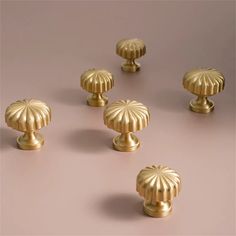 an assortment of brass knobs on a pink background