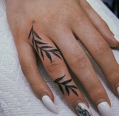 a woman's hand with white nails and black leaves on her left thumb, holding onto a towel